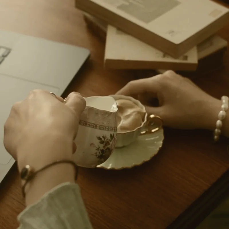 Two coffee cups on a table between two people mid-conversation.